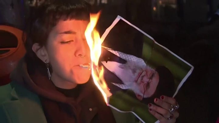 Anti-Iranian regime protesters light cigarettes using photos of Ayatollah Ali Khamenei
